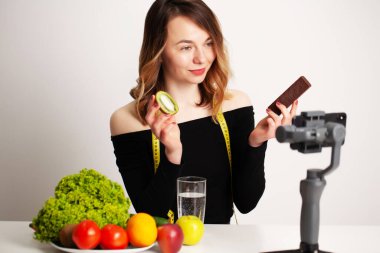 Deniz fenerinde genç bir kadın kilo verme ve sağlıklı beslenmeyle ilgili bir blog yazıyor.