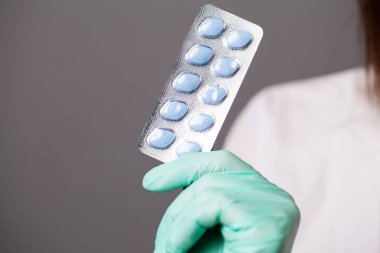 Eldivenli doktor erkeklerin cinsel sağlığı için ilaç tutuyor.