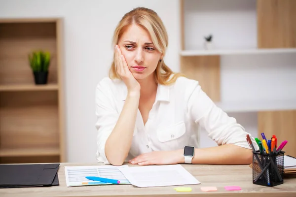 Young female business woman feels a toothache in her office