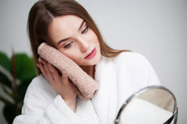 Очищення шкіри обличчя, молода жінка тримає рушник біля шкіри обличчя після миття обличчя — стокове фото