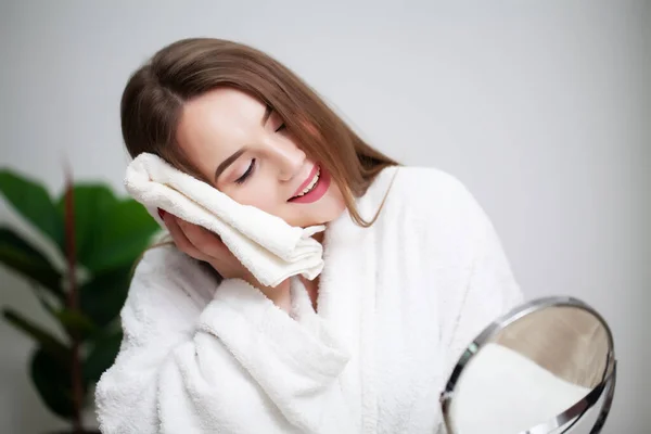 Очищення шкіри обличчя, молода жінка тримає білий рушник біля шкіри обличчя після миття обличчя — стокове фото