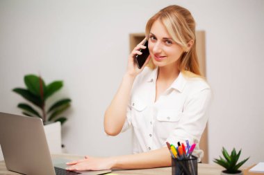 İş kadını ofisinde telefonla konuşuyor.