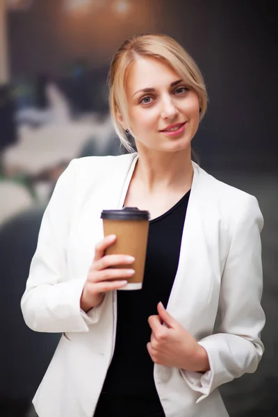 Business woman manager drinking coffee from a paper cup in the companys office — Stock Photo, Image