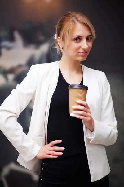 Business woman manager drinking coffee from a paper cup in the companys office — Stock Photo, Image
