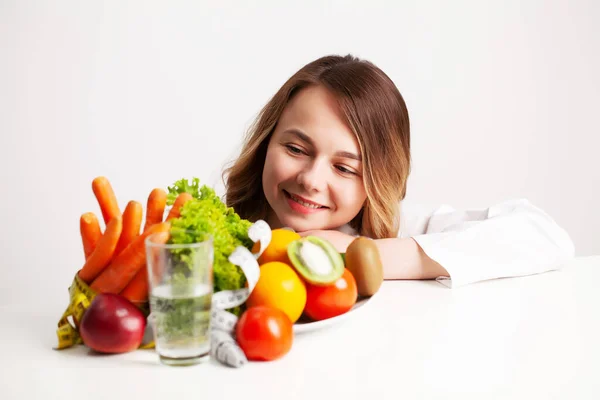 Nutricionista en su oficina mirando un plato lleno de verduras y frutas frescas — Foto de Stock