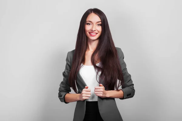 Succes zakenvrouw met donker haar staan op een grijze achtergrond — Stockfoto
