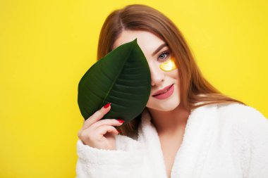 Güzel ciltli genç bir kadın göz altı cilt bakımı için yamalar yapıştırır.