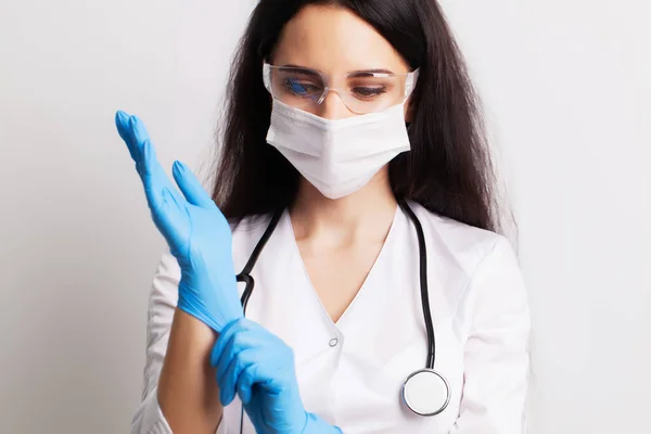 흰 코트를 입은 여자 의사는 의료용 장갑을 끼고 있다 — 스톡 사진
