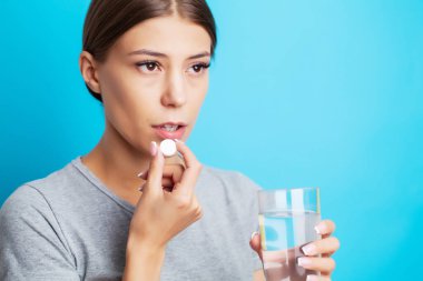 Diş ağrısı çeken bitkin bir kadın ağrı kesici alır.