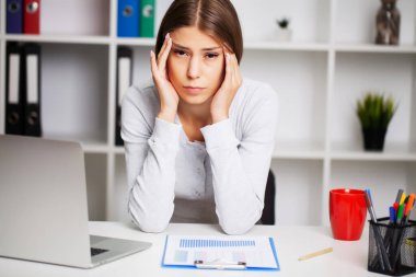 Ofisteki yorgun kadın şiddetli baş ağrısından muzdarip.