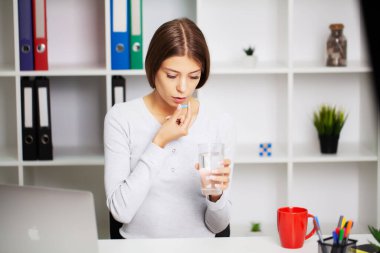 Diş ağrısı çeken bitkin bir kadın ağrı kesici alır.