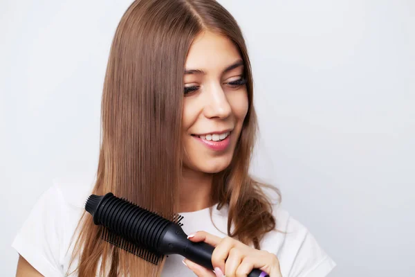 Schöne junge Frau verwendet einen Haarglätter, um ein schönes Styling zu machen — Stockfoto