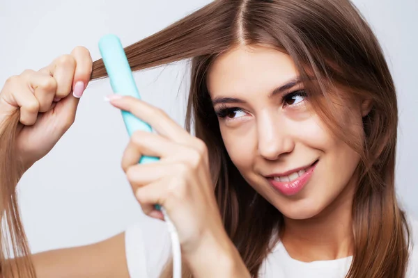 Bella giovane donna utilizza una piastra per capelli per fare uno stile bello — Foto Stock
