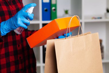 Koruyucu eldivenli bir kadının alışverişi dezenfekte etmesine yakın.