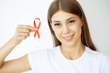 Elinde kırmızı kurdele tutan bir kadın AIDS 'i yendikten sonra kritik bir durumdan çıktı.