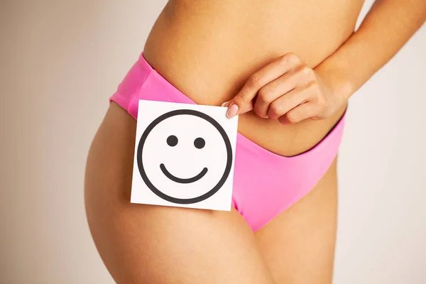 Primer plano de la mujer con esbelta figura sosteniendo cerca de la tarjeta del vientre con sonrisa sonriente — Foto de Stock