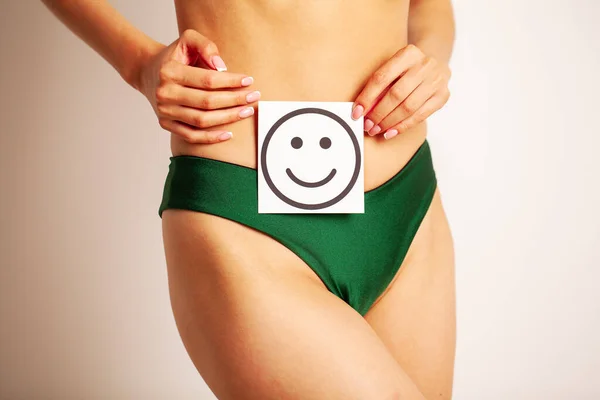 Primer plano de la mujer con esbelta figura sosteniendo cerca de la tarjeta del vientre con sonrisa sonriente — Foto de Stock
