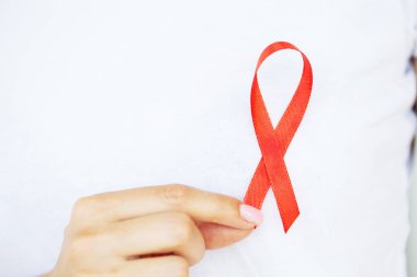 Elinde kırmızı kurdele tutan bir kadın AIDS 'i yendikten sonra kritik bir durumdan çıktı.