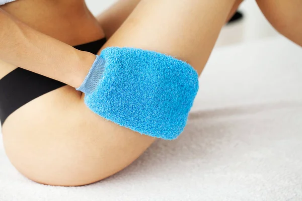 Brazo de mujer sosteniendo cepillo seco azul en la parte superior de su pierna, tratamiento de celulitis y cepillado en seco . — Foto de Stock