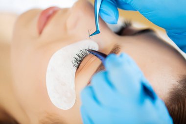 Kirpik uzatma ustası güzel bir kadına kirpiklerini uzatır.