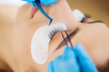 Kirpik uzatma ustası güzel bir kadına kirpiklerini uzatır.