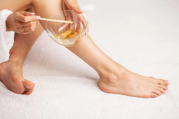 Woman with perfect skin on her legs applied wax to remove hair