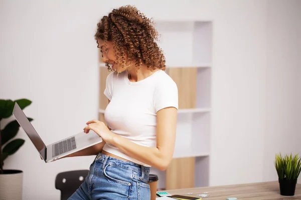 Hermosa mujer de negocios con una sonrisa en su cara trabajando en la oficina en un ordenador portátil —  Fotos de Stock