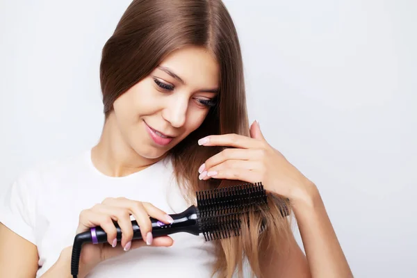 Junge Frau mit luxuriösen Haaren richtet es mit einem Lockenstab auf — Stockfoto