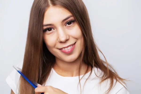Молодая женщина расчесывает свои красивые волосы расчёской — стоковое фото