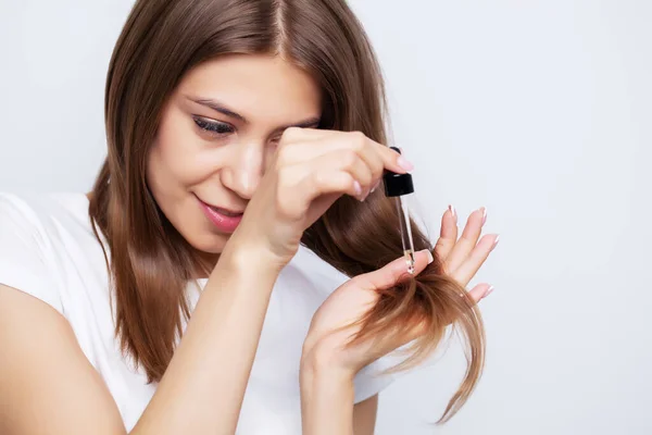 Young woman with luxurious hair applies conditioner for hair care