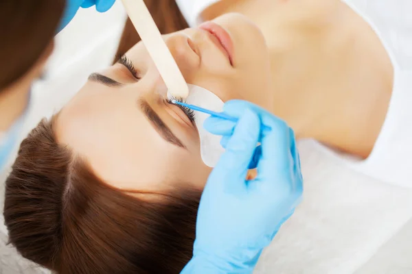 Mujer joven en un estudio de belleza en un procedimiento de extensión de pestañas —  Fotos de Stock