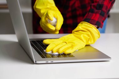 Kadın masadaki tozdan dizüstünü siliyor.