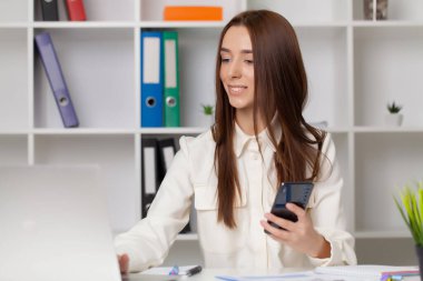 Masadaki ofiste çalışan genç bir kadın.