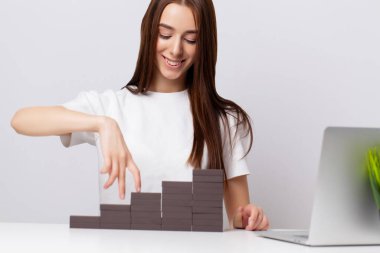 Güzel genç bayan ofisteki masada tahta küpler yapıyor.