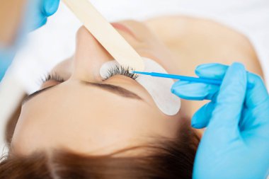 Kirpik Uzatma Prosedürü, kadın kirpiklerini uzatan profesyonel stilist.