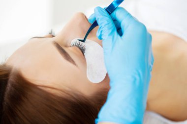 Kirpik Uzatma Prosedürü, kadın kirpiklerini uzatan profesyonel stilist.