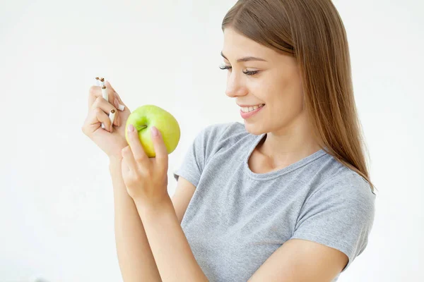 Deja de fumar, mujer sosteniendo un cigarrillo roto y una manzana verde —  Fotos de Stock