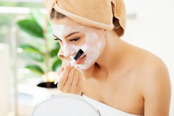 Femme applique un masque en argile blanche pour les soins de la peau du visage dans la salle de bain de luxe hôtel — Photo