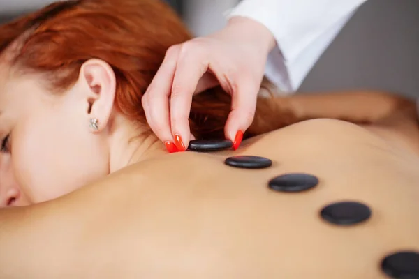 Junge Frau bekommt heiße Steinmassage im Wellness-Salon. — Stockfoto