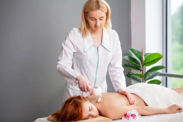 Mujer joven con el pelo rojo recibe un masaje de espalda terapéutico — Foto de Stock