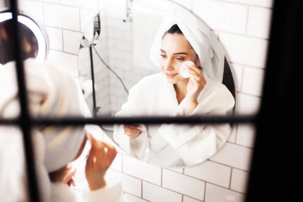 Mujer joven sonriente lavándose la cara con esponja de limpieza facial en el baño — Foto de Stock