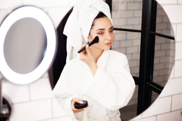 Hermosa mujer usando cepillo para el maquillaje diario en el baño — Foto de Stock