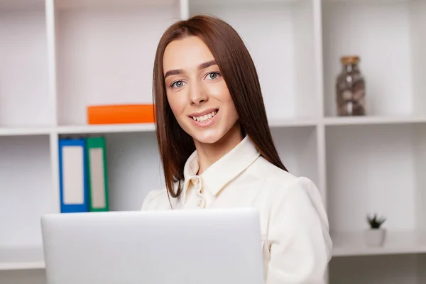 Jonge mooie zakenvrouw werken op laptop in helder modern kantoor — Stockfoto