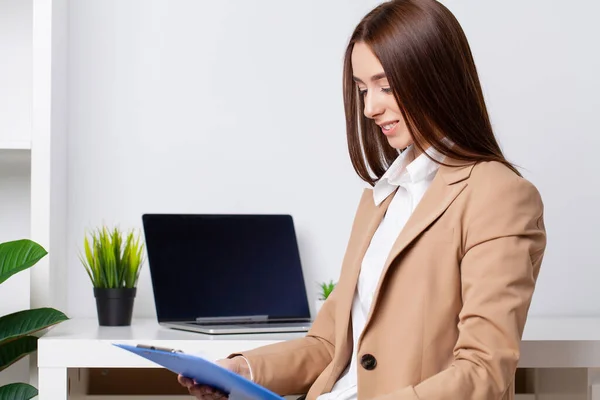 Ung vacker affärskvinna som arbetar på laptop i ljusa moderna kontor — Stockfoto