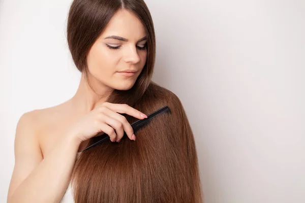 Krásná žena hřeben její zdravé dlouhé vlasy — Stock fotografie