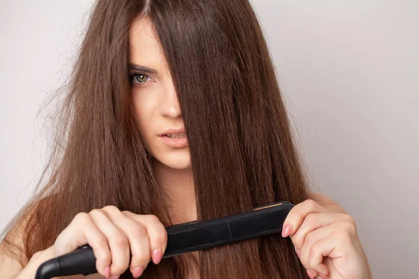 Frau mit schönen langen glatten Haaren mit einem Haarglätter — Stockfoto