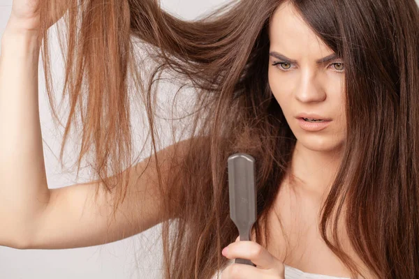 Very upset young woman with comb and problem loss hair. — Stock Photo, Image