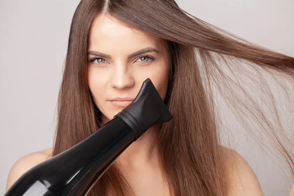 Hermosa mujer sonriente secando su cabello largo con secadora — Foto de Stock