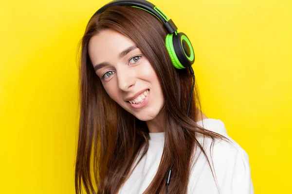 Beautiful young sexy girl DJ listening music in green headphones on a yellow background — Stock Photo, Image