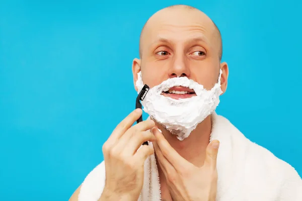 英俊男子用剃须刀刮胡子并向别处看的画像 — 图库照片